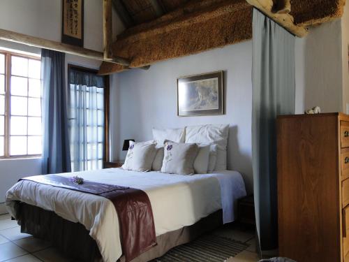 a bedroom with a bed with white sheets and pillows at Mokoya Lodge in Hekpoort