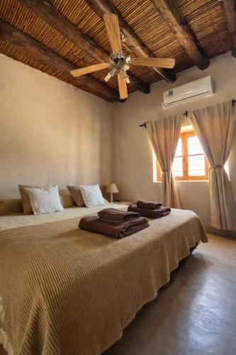 a bedroom with a large bed with a ceiling fan at Huaco Casa de Campo in Belén