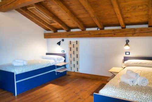 a bedroom with two beds and wooden ceilings at Authentic Lake Como Home near Bellagio in Limonta