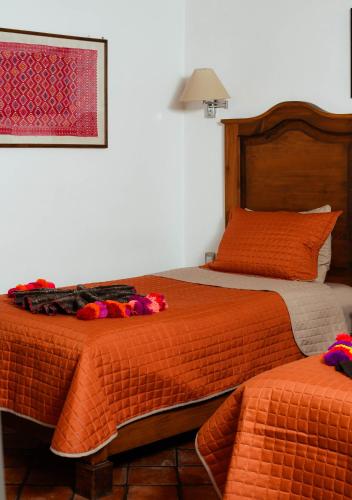 a bedroom with two beds with orange comforters at Hotel El Zaguán Histórico in San Cristóbal de Las Casas