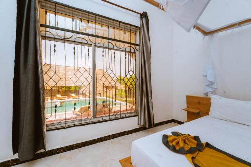 a bedroom with a window with a view of a pool at Farashuu Luna Hotel in Kendwa