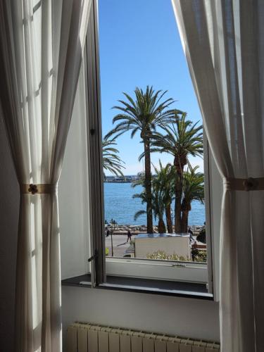a window with a view of the ocean and palm trees at Acquamarina in Rapallo