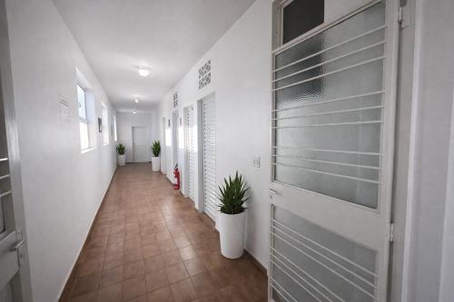 a hallway with white walls and a door with plants at Hotel Americano in Americano Brasil
