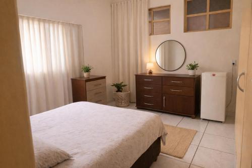 a bedroom with a bed and a mirror and a refrigerator at Hotel Americano in Americano Brasil