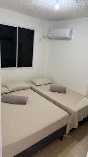 two beds in a room with a window at Lazer na linha verde in Camaçari