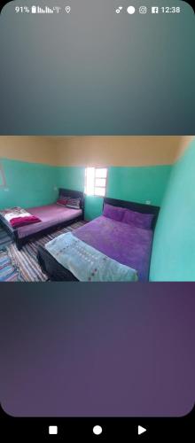 a bedroom with two beds with purple sheets at Gite ousalem timichi in Timichchi