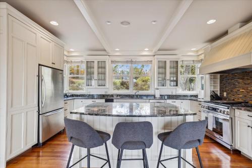 a kitchen with white cabinets and a large island with chairs at Weeks Hill Meadows in Stowe