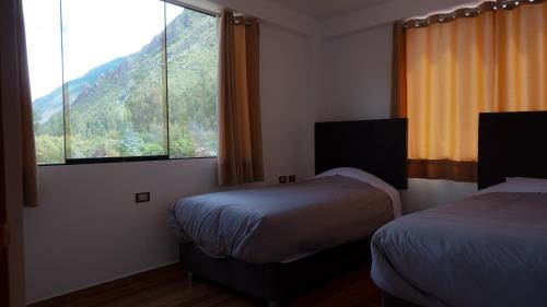 a bedroom with two beds and a large window at Depa Urubamba in Urubamba