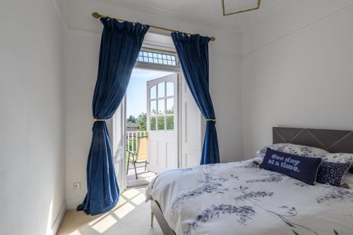 a bedroom with blue curtains and a bed and a door at Drumnacree House, Alyth in Alyth