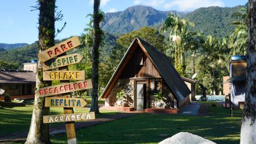 a sign in front of a small house with mountains at Chácara bello Rio in Guaratuba