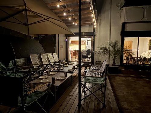 a group of tables and chairs with umbrellas in a room at ゲストハウス三浦 サウナ Bbq 一棟貸し 最大13名 in Miura