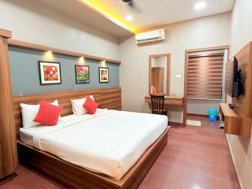 a bedroom with a large white bed with red pillows at Century Regency in Cochin