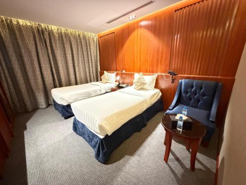 a hotel room with two beds and a blue chair at فندق تمكين-TamkeenHotel- تابع لعلامة كلاديوم- A Cladium brand in Medina