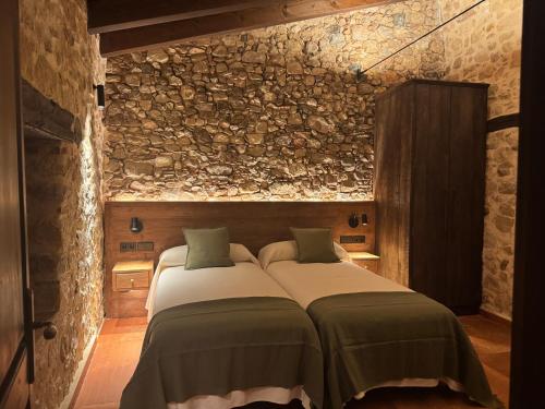 a bedroom with two beds and a stone wall at Masia de Can Roig in Riells