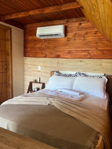 a bedroom with a bed with a wooden wall at Refúgio do Lago in Fraiburgo
