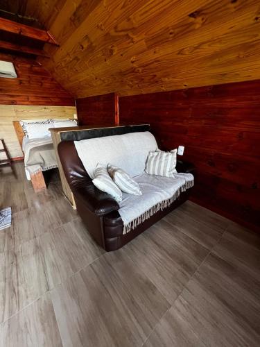 a leather couch sitting in a room in a cabin at Refúgio do Lago in Fraiburgo