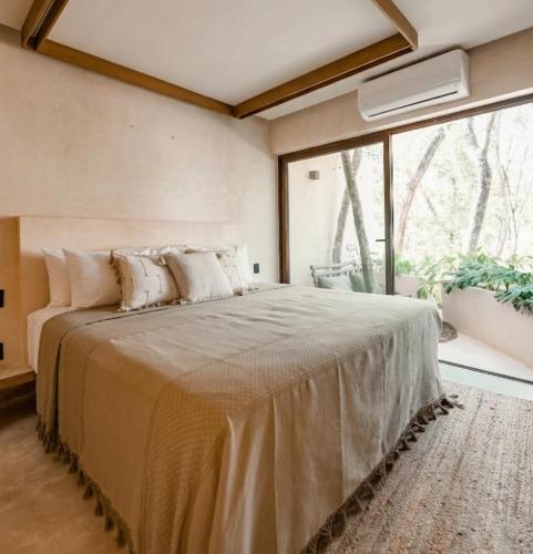 a bedroom with a large bed with a large window at Taio Tulum in Tulum