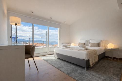 a white bedroom with a large bed and a large window at ins Ígnea in Madalena