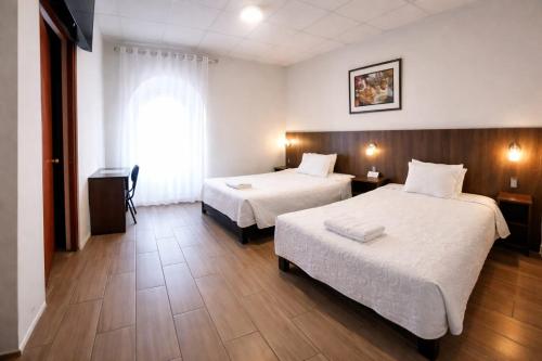 a hotel room with two beds and a window at El Solar Inn in Arequipa