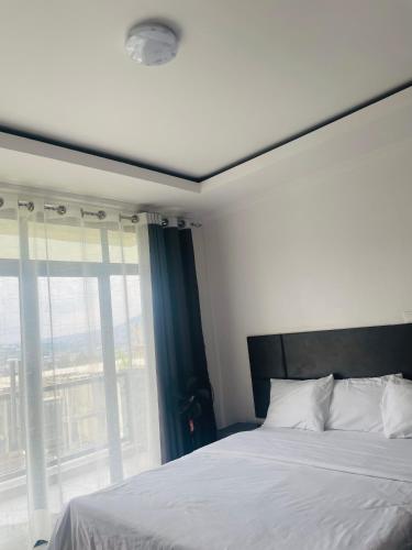 a bedroom with a bed and a large window at Kigali Clever stay Villaa in Kigali