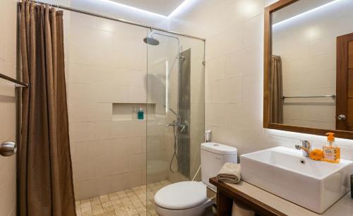 a bathroom with a shower and a toilet and a sink at Naksa Homestay Sanur in Sanur