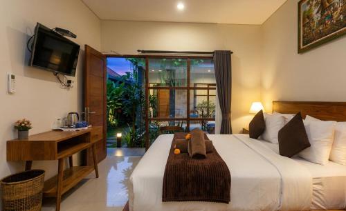 a bedroom with a bed and a desk and a television at Naksa Homestay Sanur in Sanur