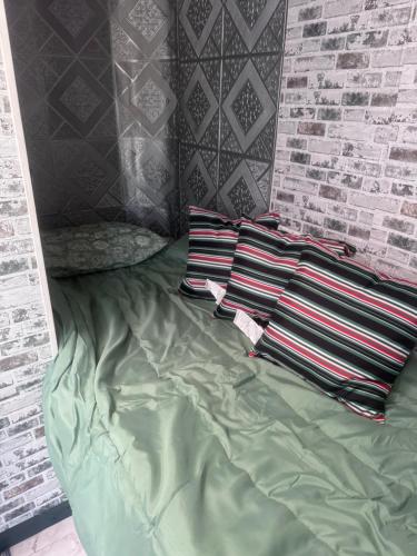 ein Bett mit drei Kissen und eine Backsteinwand in der Unterkunft Comfy camper in Tampa