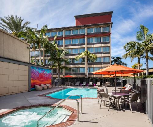 a hotel with a pool and tables and chairs and an umbrella at ALO Hotel by Ayres, Orange in Anaheim