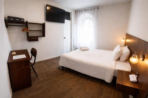 a bedroom with a bed and a desk and a window at El Solar Inn in Arequipa