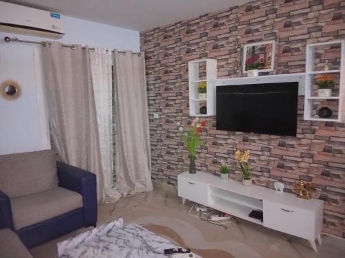 salon z telewizorem na ceglanej ścianie w obiekcie Kassy House w mieście Dakar