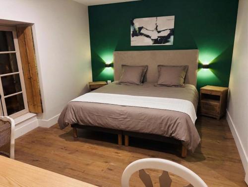 a bedroom with a bed with a green wall at Auberge de l'Etoile in Vignory
