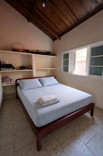 a bedroom with a bed in a room with a window at Casa do Sapê 5 dormitórios em Ubatuba in Ubatuba