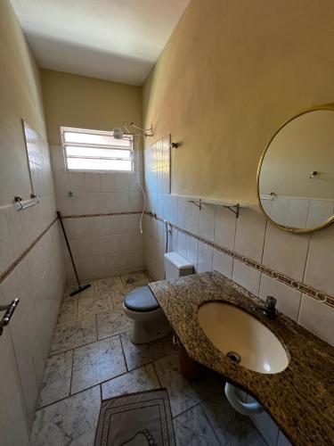 a bathroom with a sink and a toilet and a mirror at Casa do Sapê 5 dormitórios em Ubatuba in Ubatuba