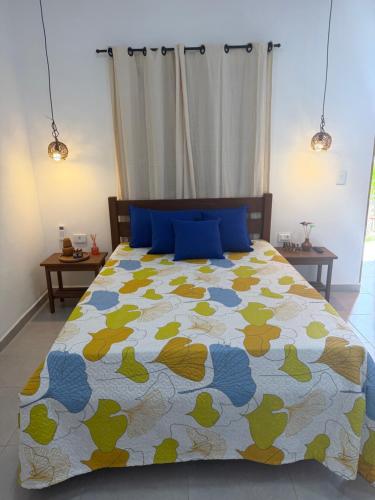 a bedroom with a bed with a colorful comforter at Casa amarela Recanto Doce Lar in Gravatá