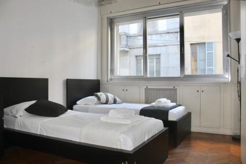 two beds in a room with a window at Iconic 3-BR Home Steps from Duomo in Milan