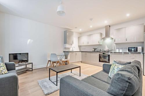 a living room with a couch and a kitchen at Modern, City living Apartments- Private parking in Oxford