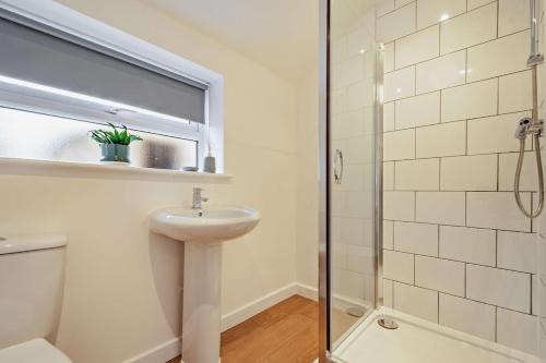 a bathroom with a sink and a glass shower at Modern, City living Apartments- Private parking in Oxford