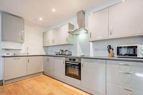 a white kitchen with white cabinets and appliances at Modern, City living Apartments- Private parking in Oxford