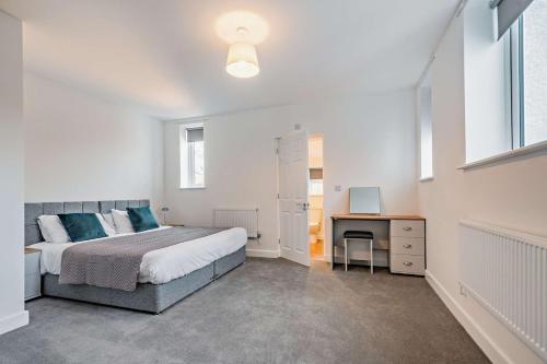 a bedroom with a large bed and a desk at Modern, City living Apartments- Private parking in Oxford