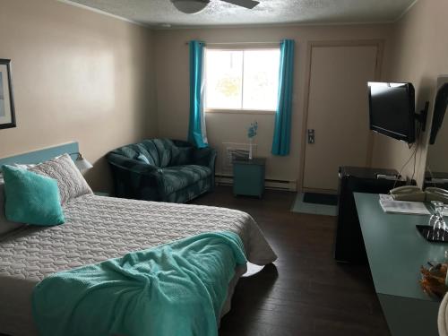 a bedroom with a bed and a chair and a window at Motel Belle Riviere in Saint-Jean-sur-Richelieu