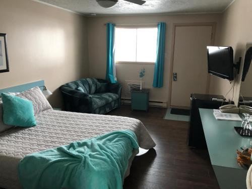 a bedroom with a bed and a chair and a window at Motel Belle Riviere in Saint-Jean-sur-Richelieu
