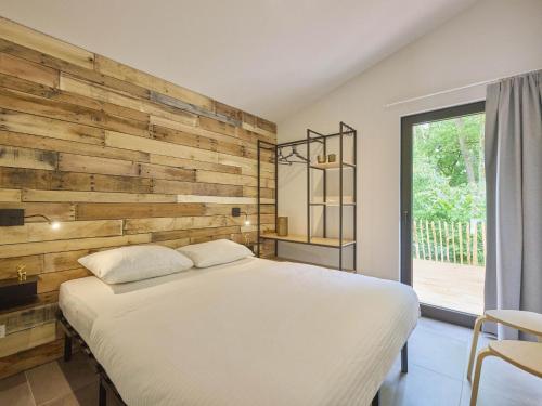 a bedroom with a white bed and a wooden wall at Cabin 22 in Zutendaal