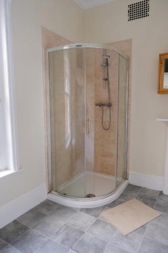 a shower with a glass door in a bathroom at Two Perfect for large groups and secured free parking in Reading