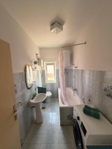 a bathroom with a tub and a sink and a washing machine at Apartments by the sea Ugljan - 8264 in Ugljan