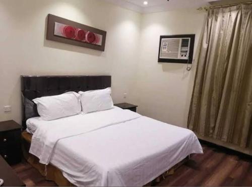 a bedroom with a bed with white sheets and a window at شقق النسيم in Quai