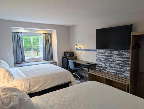 a hotel room with two beds and a desk at Greenville Pelham Inn by IHG in Greenville