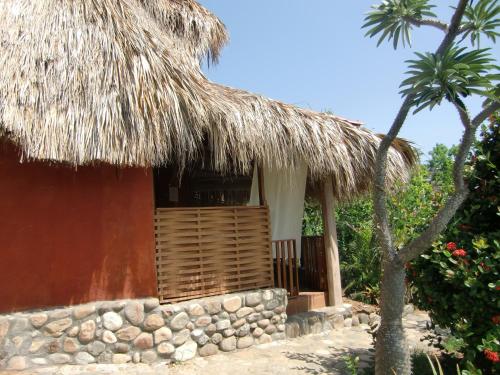 chata ze słomianym dachem i palmą w obiekcie Villa Escondida w mieście Zipolite
