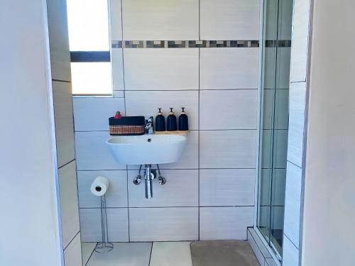 a white tiled bathroom with a sink and a shower at Modern Luxe Escape in Kempton Park