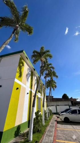 a yellow and white building with palm trees and a car at Hotel Jardin in San Cristóbal