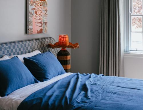 a bedroom with a bed with blue sheets and a lamp at Sona Molong in Molong